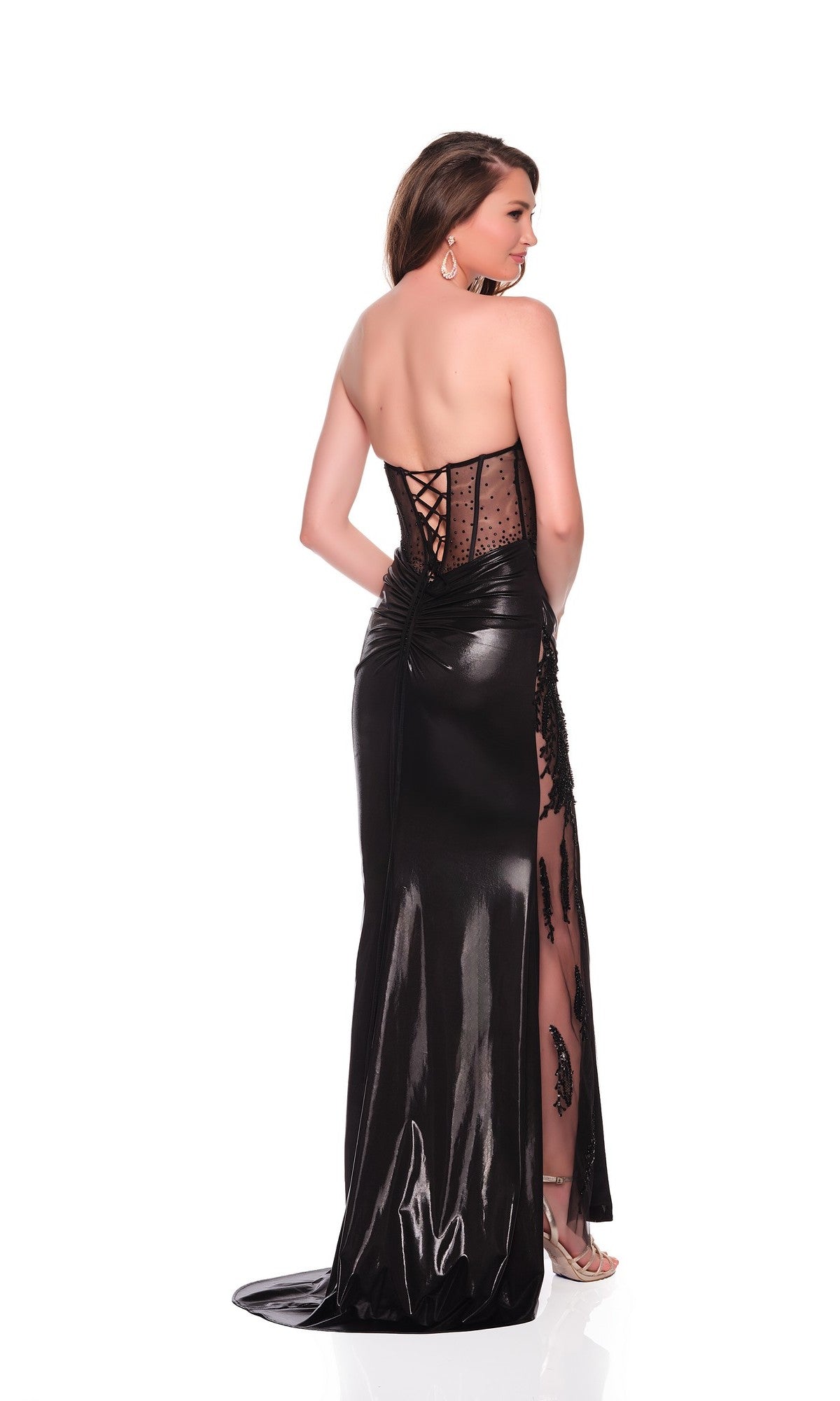 A woman faces away in the Long Prom Dress: Dave and Johnny 12586, a black strapless gown with a lace-up sheer corset bust, elegant black lace accents, and a glossy floor-length leather skirt with see-through sides.